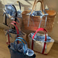 Five open-top bags with Casa de Telas drawstring tie-on liners on a wooden floor.